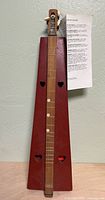 Full front view of red wooden lap dulcimer with heart sound holes and fretboard