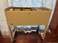 Full view of beige metal file cart on casters, folders visible