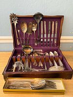 Overall view of flatware set in open wooden chest showing upper and lower compartments