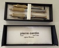 Open box showing two matching pens secured by white band