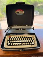 Typewriter open in its case showing keyboard and branding