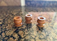 Three small turned wooden candle holders on countertop
