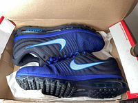 Top view of both shoes inside original box showing black upper, royal blue accents, full-length air sole