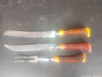 Set laid out: serrated knife, carving knife, fork with Bakelite handles