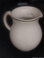 Front profile of cream ribbed pitcher showing spout and handle