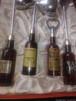 Open box showing four bottle-handled bar tools in satin lining