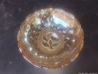 Top view of bowl showing marigold iridescence, scalloped rim, raised floral design