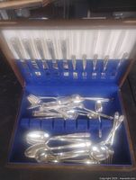Open chest showing knives, forks in lid slots and assorted spoons and forks in base