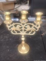 Front view of brass candlestick showing three arms and lion design