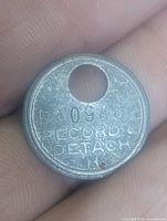 Front of round metal tag showing code FA0948 and text RECORD DETACH