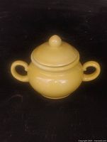 Front view of yellow ceramic sugar bowl with lid in place