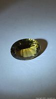 Front angled view of the oval citrine showing concave facets and golden color