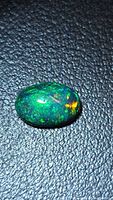 Front view of black opal showing green and orange play-of-colour