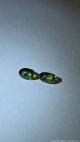 Pair of oval green sapphires on neutral background