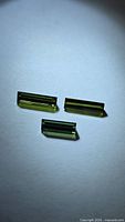 Three baguette-cut green tourmaline stones on white background