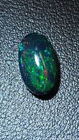 Front view of oval Ethiopian black opal showing green and red flashes