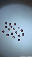Group of 17 pink-purple round sapphires on white background