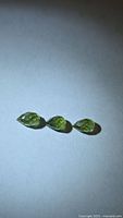 Three loose green briolette sapphires on neutral background