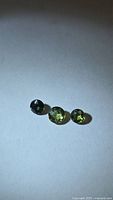 Three round green sapphires on white background