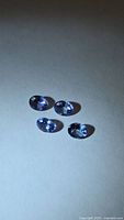 Four oval blue-purple faceted stones on light background