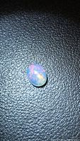 Front view of oval cabochon opal displaying multicolor fire