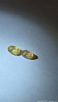 Two pastel yellow oval gemstones on neutral background