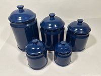 Front view of all five blue ceramic canisters with lids in place
