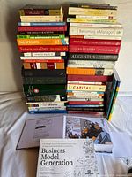 Two vertical stacks of approx. 45 books with Business Model Generation workbook and open Rusty Brown graphic novel visible