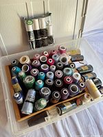 Overall view of plastic bin containing numerous thread cones and sealed 12-pack