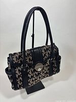 Full view of Michael Kors MK monogram satchel on stand showing double handles and overall design