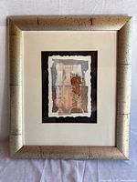 Full view of framed artwork showing metallic frame, matting and composition