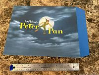 Blue folder envelope with Peter Pan cover shown alongside ruler for scale