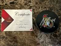 Puck with Senators logo and silver autograph beside matching COA card