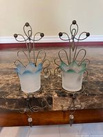 Front view of both PartyLite wall sconces showing metal frames and glass cups