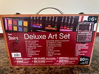 Back of wooden case showing Studio Art Deluxe Art Set packaging with contents list and 80-piece count