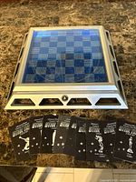 Chess board without pieces showing blue grid and metal base