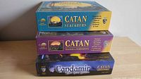 Three game boxes stacked: Catan Seafarers, Catan Traders & Barbarians, Candamir