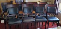Front view of eight wood and black leather dining chairs