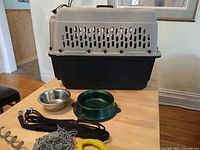 Dog crate with bowls, leash, chain, stake and toy displayed