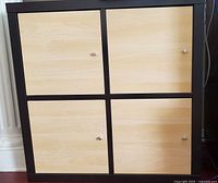 Front view of black frame storage unit with four faux birch doors
