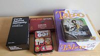 Sealed boxes and tins of the five games displayed on table