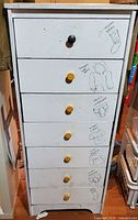 Front view of tall white seven-drawer dresser showing knobs and drawings