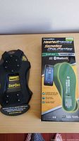 Front view of sealed Thermacell heated insoles box beside GripOns ice cleats in packaging