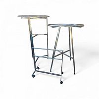 Two metal display stands with glass tops alongside rolling caddie