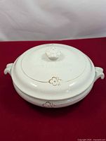 Top view of closed covered serving dish showing gold motif and floral finial