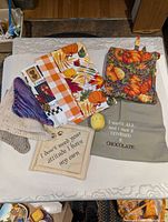 All items laid out on table: bib, potholder, three tea towels, four washcloths, timer