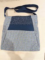 Front view of quilted shoulder bag showing patchwork design and strap