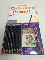 Derwent pencil tin open beside Phaidon book