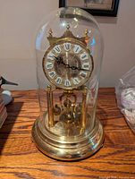 Full view of clock under glass dome on wooden surface