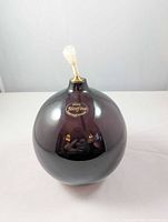 Front view showing amethyst glass body, brass collar, wick, and Józefina label